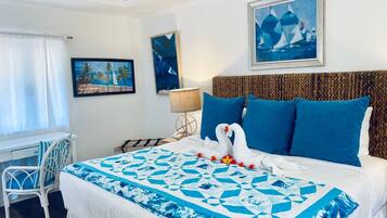 A hotel room with a bed, a desk, a chair, and artwork on the walls.