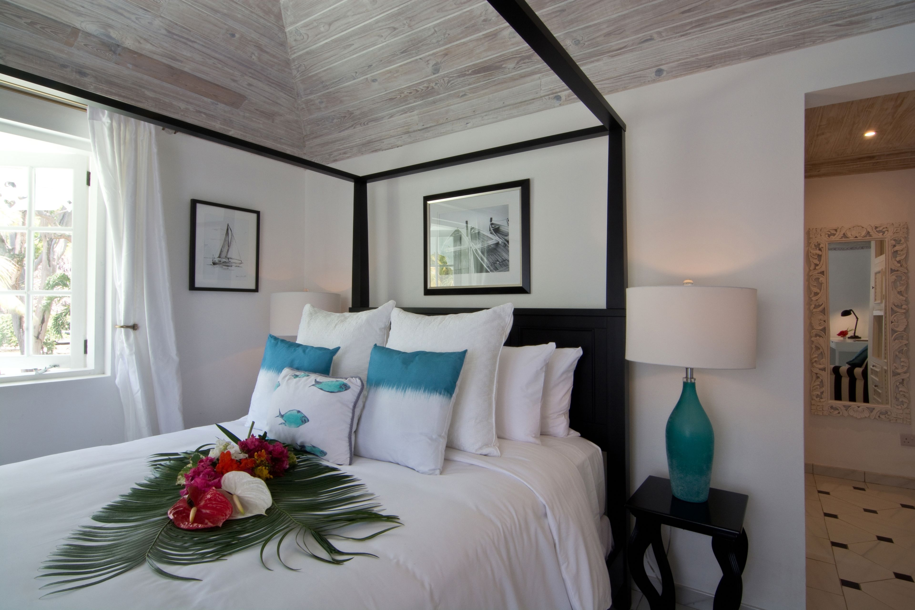 A hotel room with a bed, a nightstand, a lamp, and framed pictures on the wall.