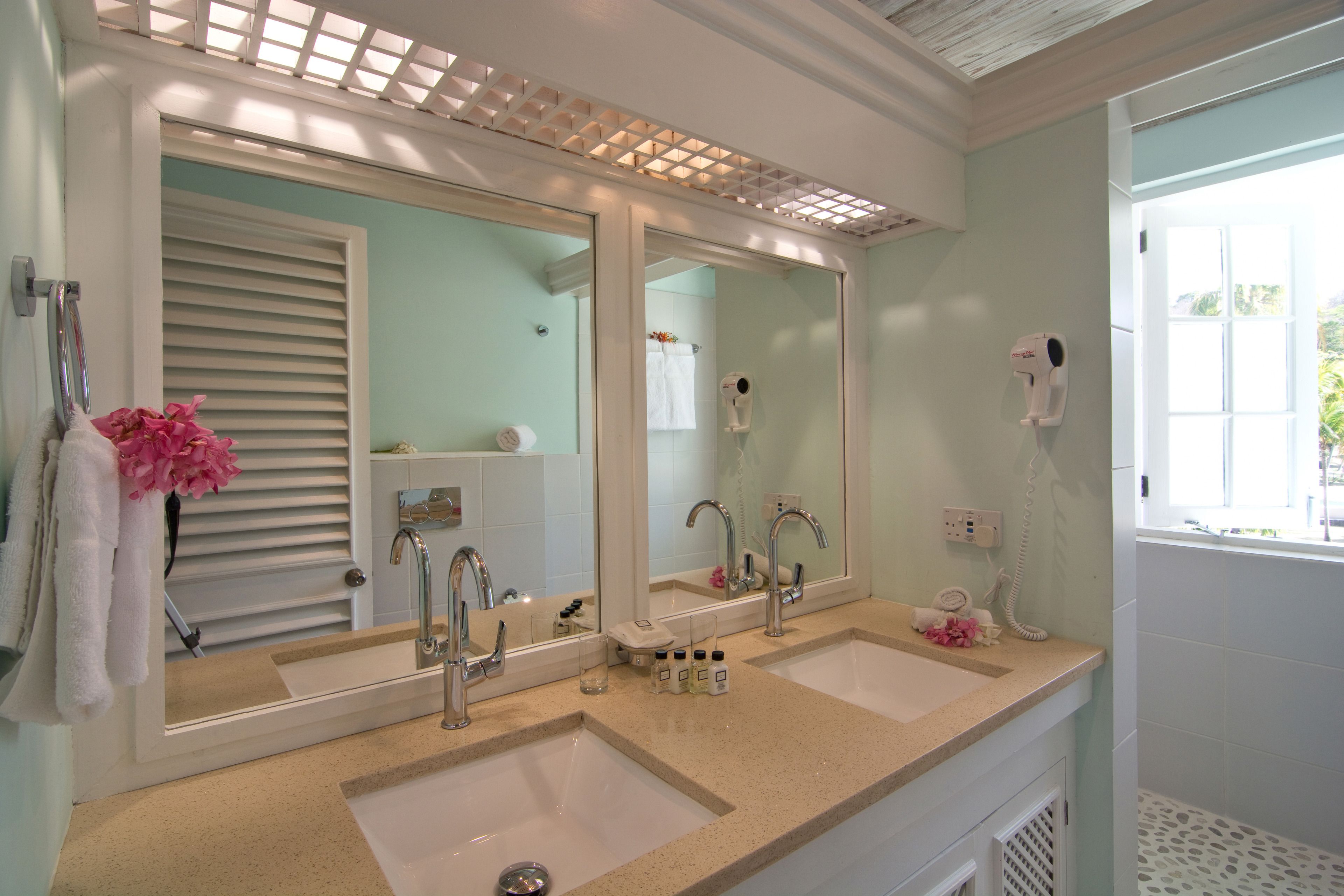 Un bagno con due lavabi, uno specchio grande e un asciugacapelli sul ripiano.