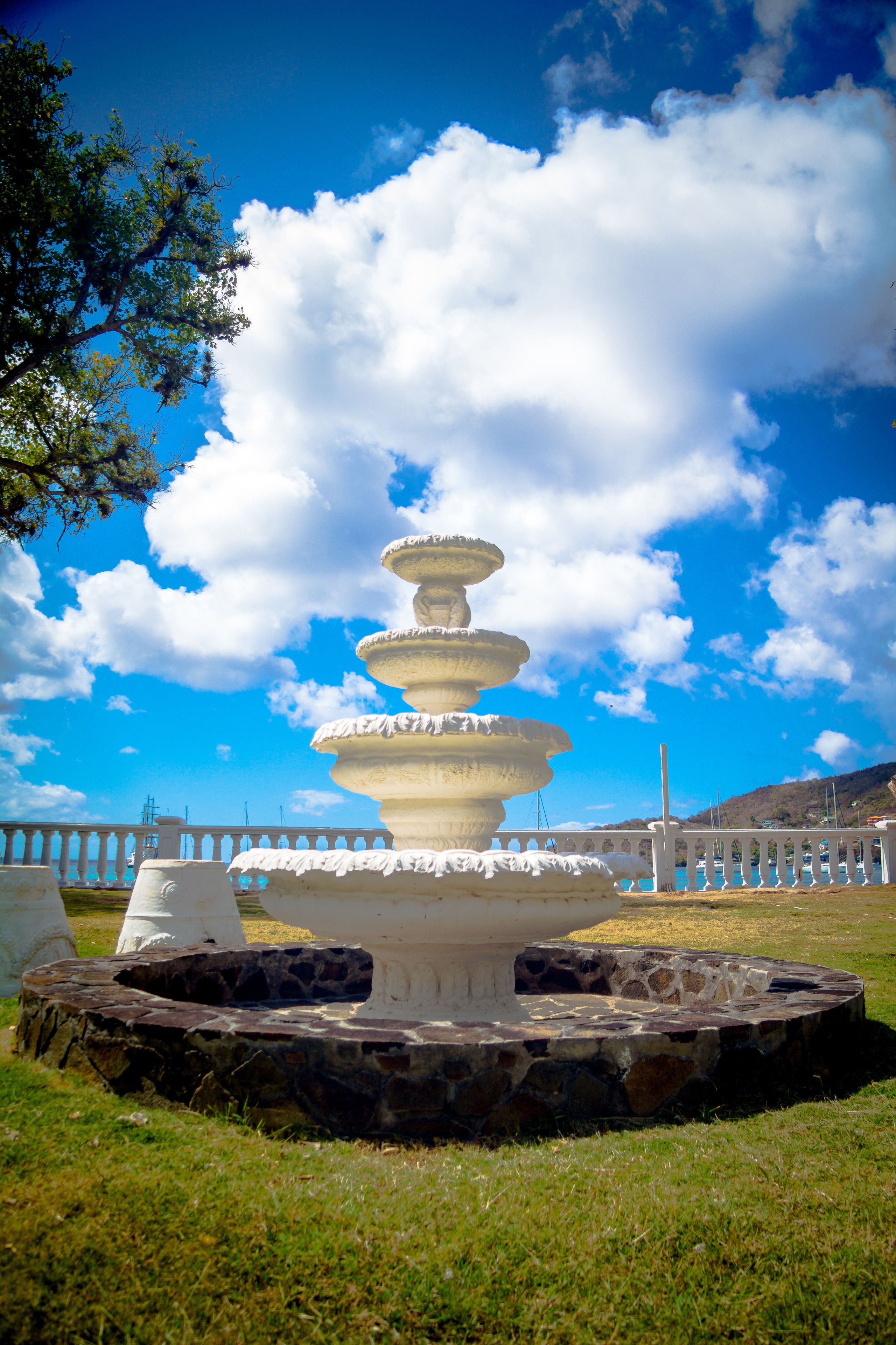 Une fontaine à plusieurs niveaux dans un parc, avec un ciel dégagé et des montagnes à l’horizon.