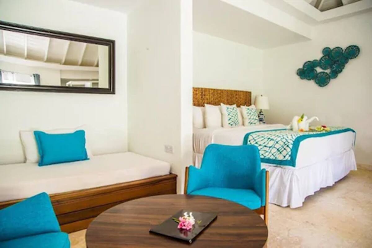 Una habitación de hotel con una cama, un sofá, una mesa redonda y un espejo montado en la pared.