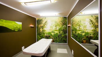 Relax in a serene space with a massage table and lush indoor garden view.
