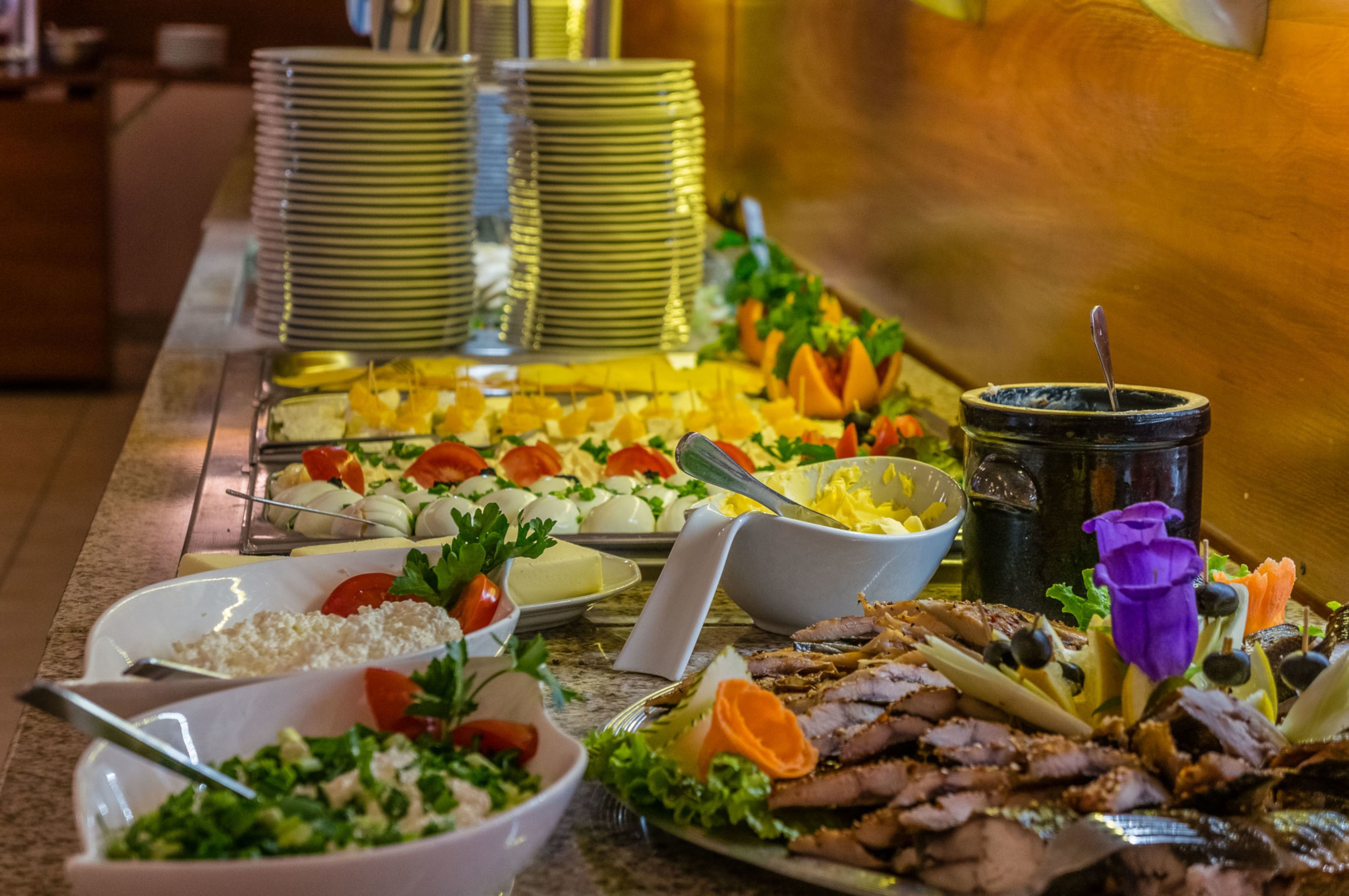 A buffet with various dishes including meats, cheeses, and salads.