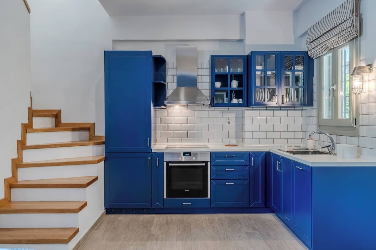 Eine moderne Küche mit blauen Schränken, einem Backofen und einer Edelstahl-Dunstabzugshaube.