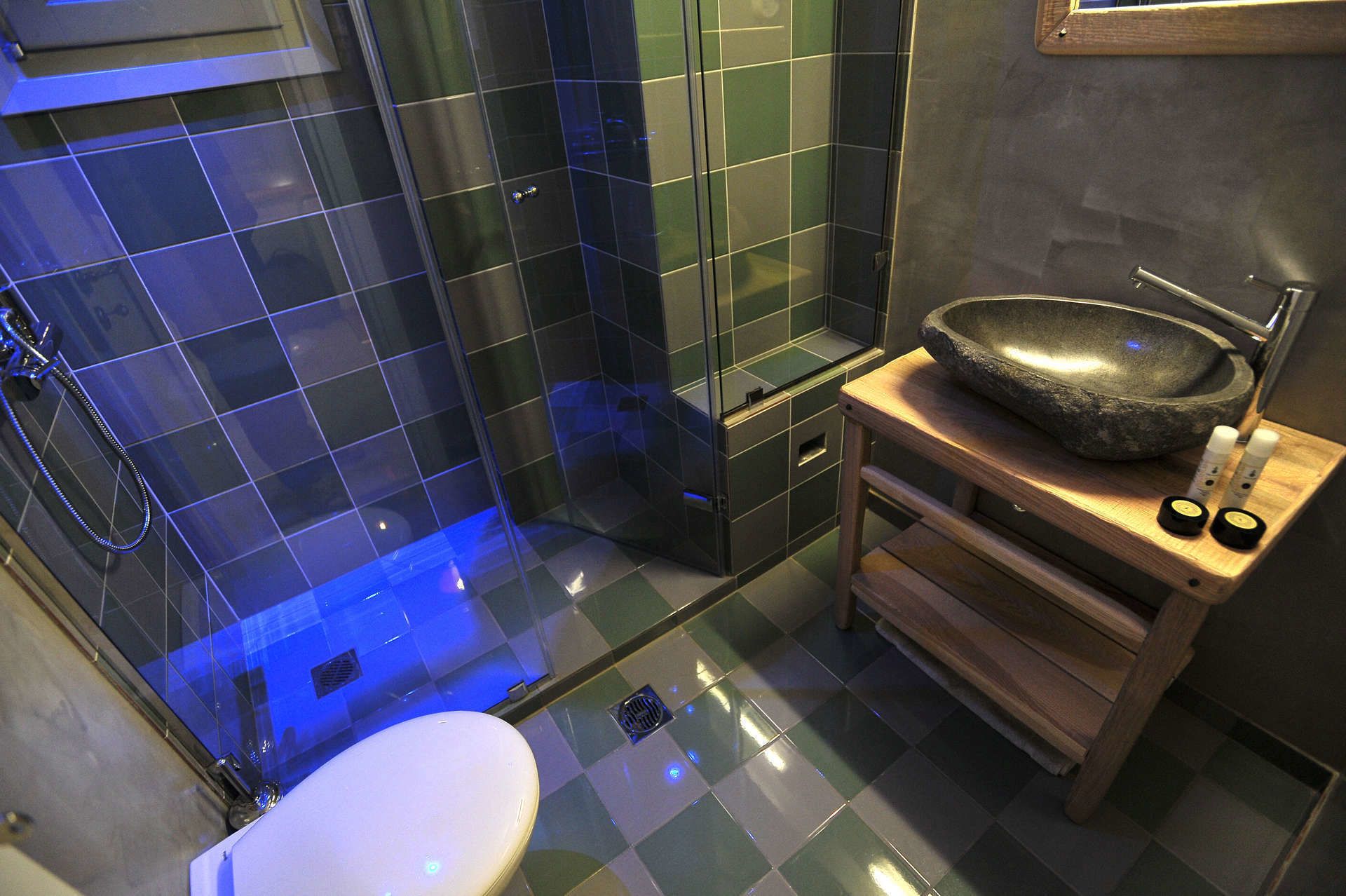 Ein modernes Badezimmer mit einer Glasdusche, einer weißen Toilette und einem Steinklopfbettchen auf einer Holzwaschbeckenbank.