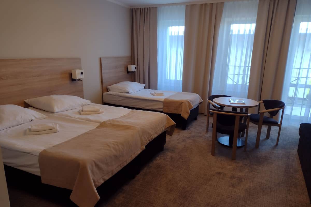 A hotel room with two beds, a small round table, and a chair.