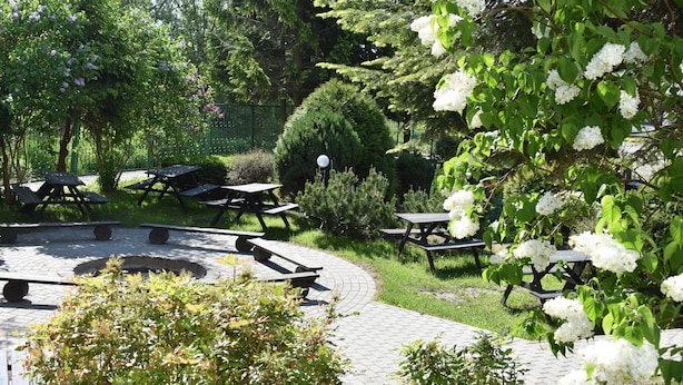 A garden with picnic tables and a circular stone feature. - Hotel NAT Sarbinowo (Sarbinowo)