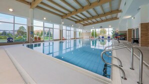 An indoor swimming pool with clear windows, wooden beams, and a view of the outside. - Hotel NAT Sarbinowo (Sarbinowo)