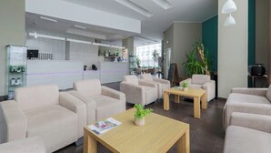 A modern hotel lobby with sofas, a reception desk, and a coffee table with a plant. - Hotel NAT Sarbinowo (Sarbinowo)
