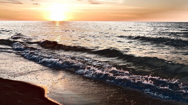 A beach with waves and a sunset. - Hotel NAT Sarbinowo (Sarbinowo)