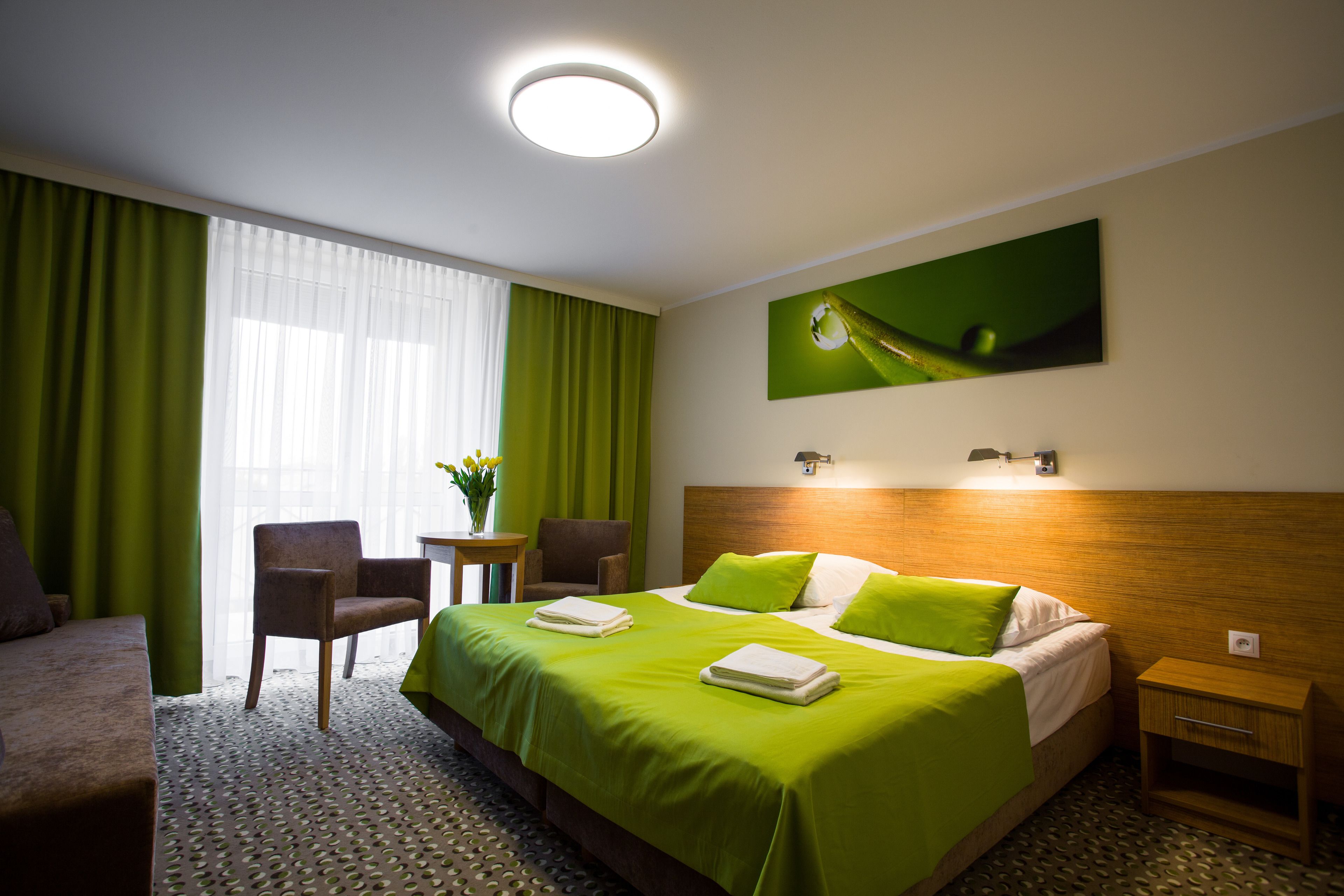 Una habitación de hotel con una cama, una silla, una mesita y una mesita de noche.