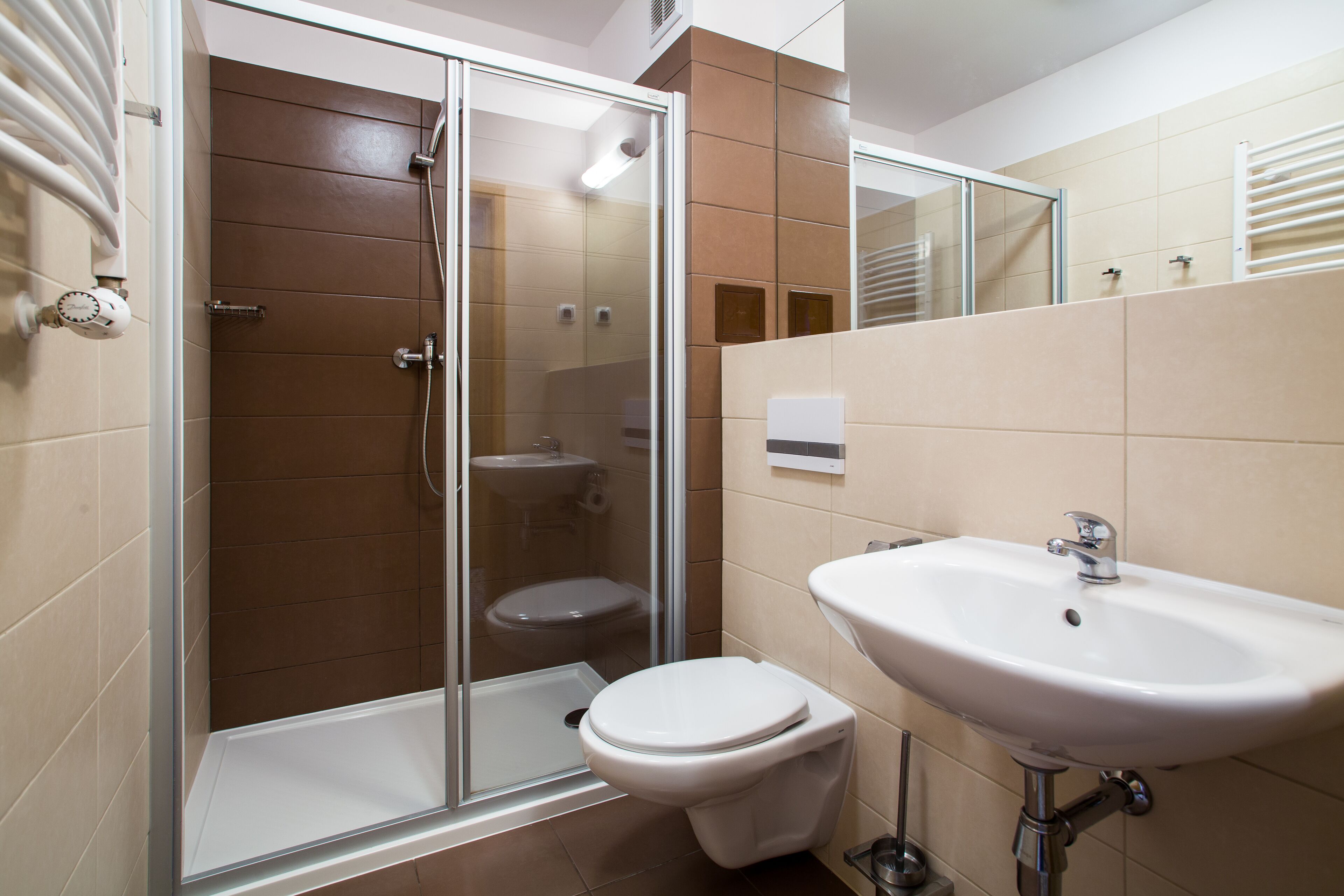 A modern bathroom with a glass-enclosed shower, a white toilet, and a sink.