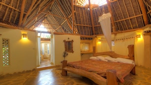 Una habitación con una cama grande, techo de madera y piso de piedra.
