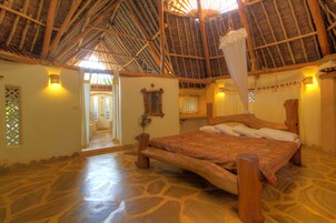 Una habitación con una cama grande, techo de madera y piso de piedra.