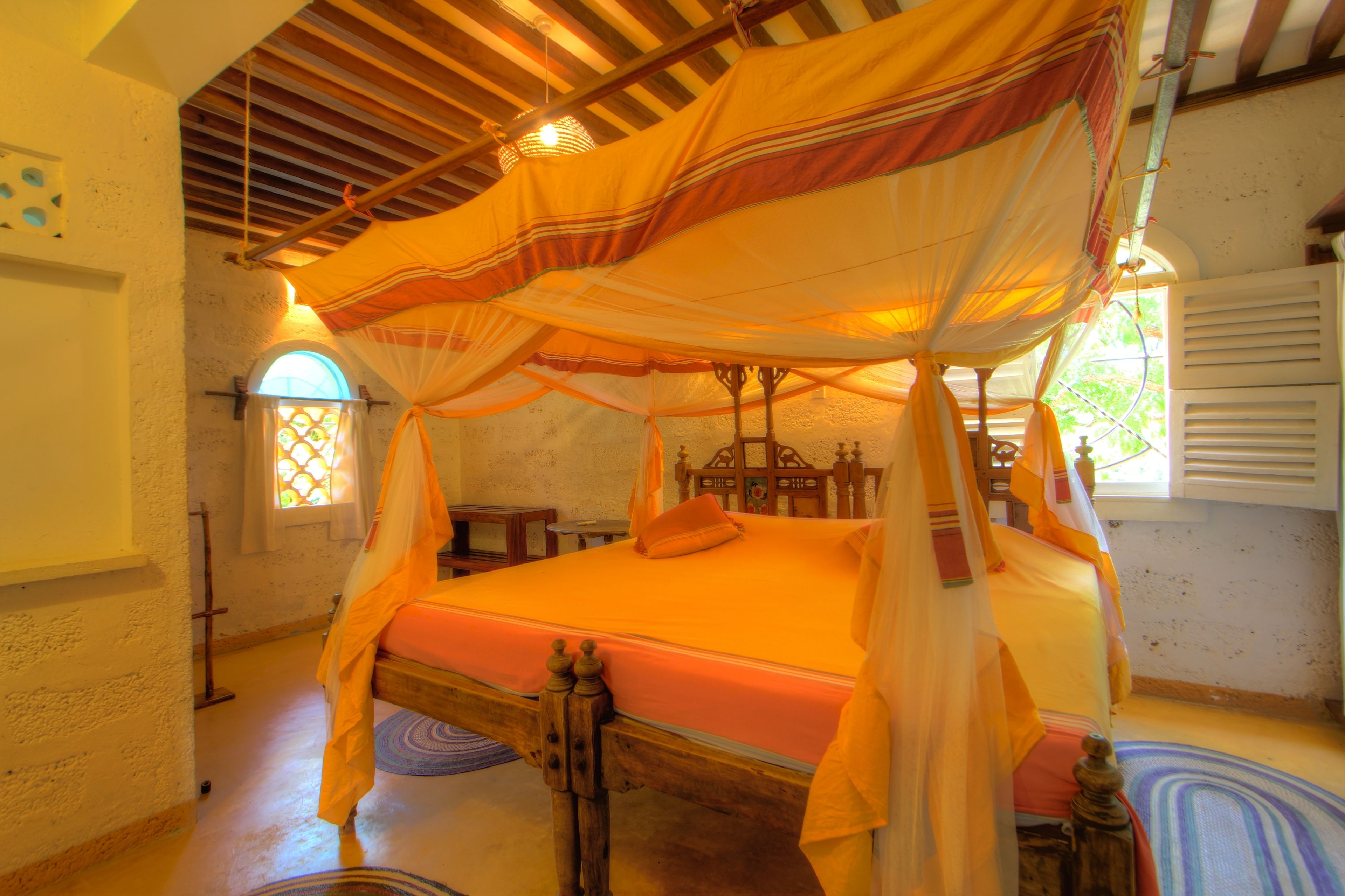 Ein Zimmer mit Himmelbett, Holz-Kopfteil und Baldachin.