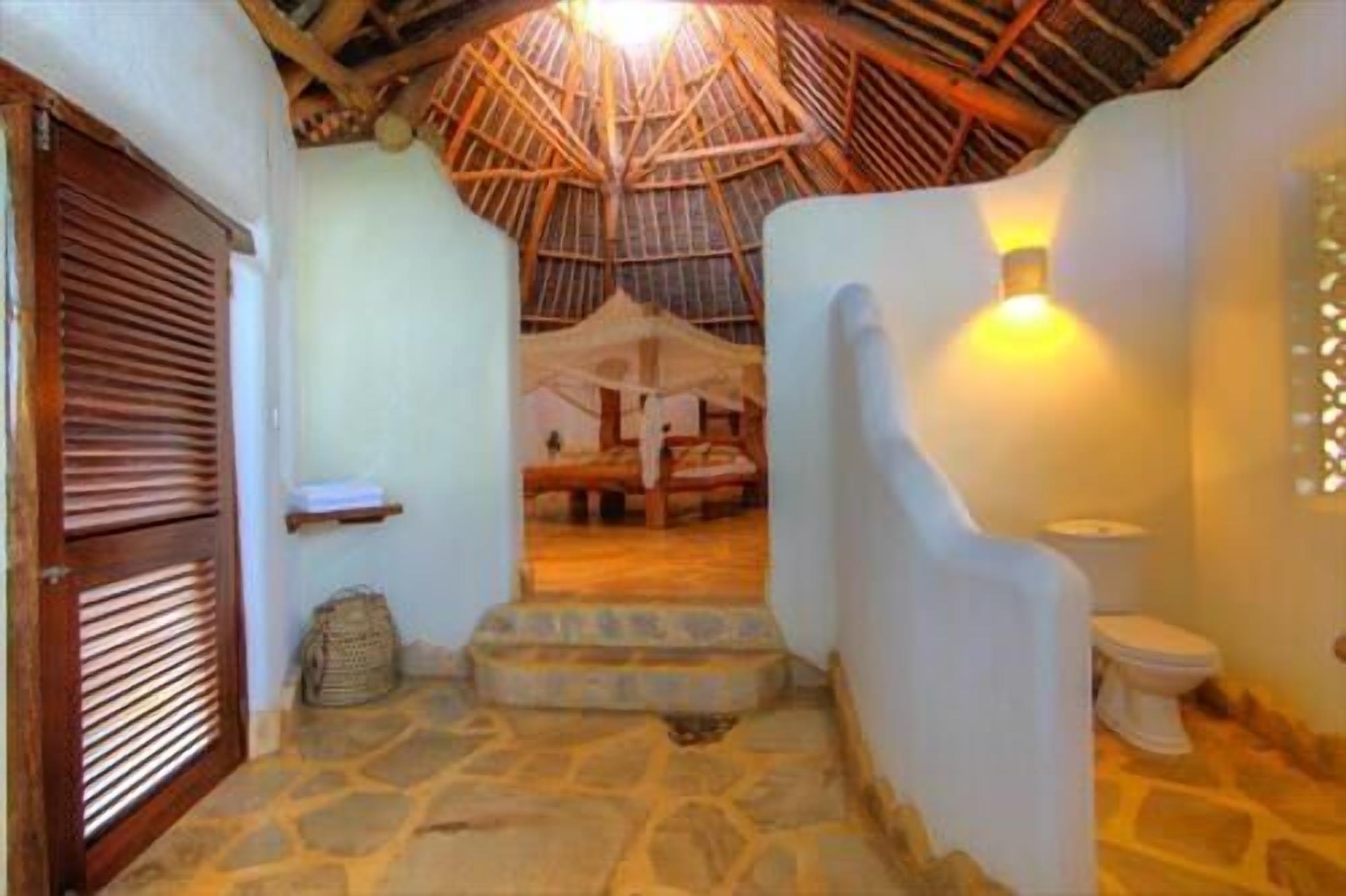 A staircase leading to a room with a thatched roof, a bed, and a small table.