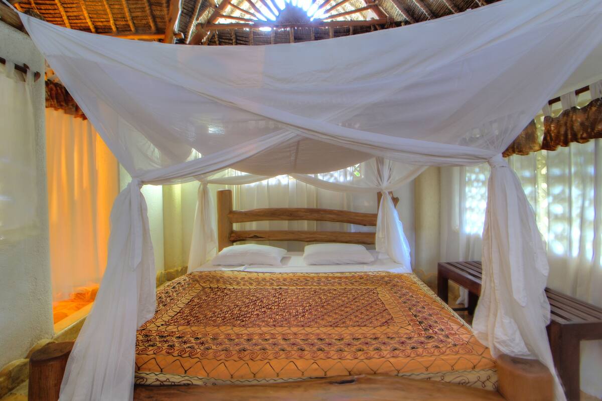 A bed with a canopy, wooden headboard, and patterned bedspread.