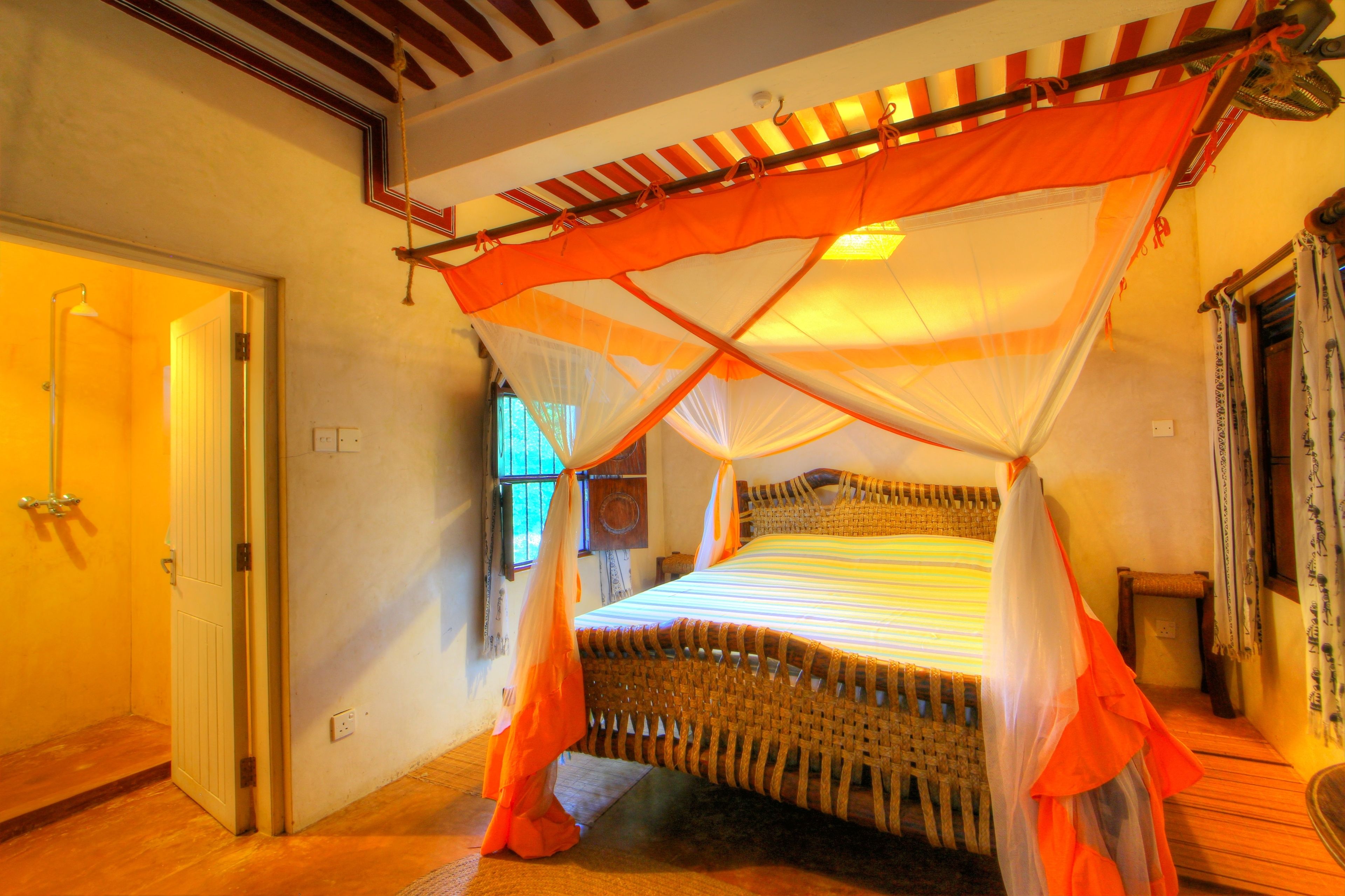 A room with a bed under a canopy, a door, and a window.