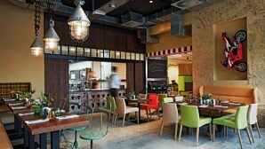 A restaurant with a bar area, multiple dining tables, and colorful chairs. - FREIgeist Einbeck - A Member of Design Hotels™ (Einbeck)