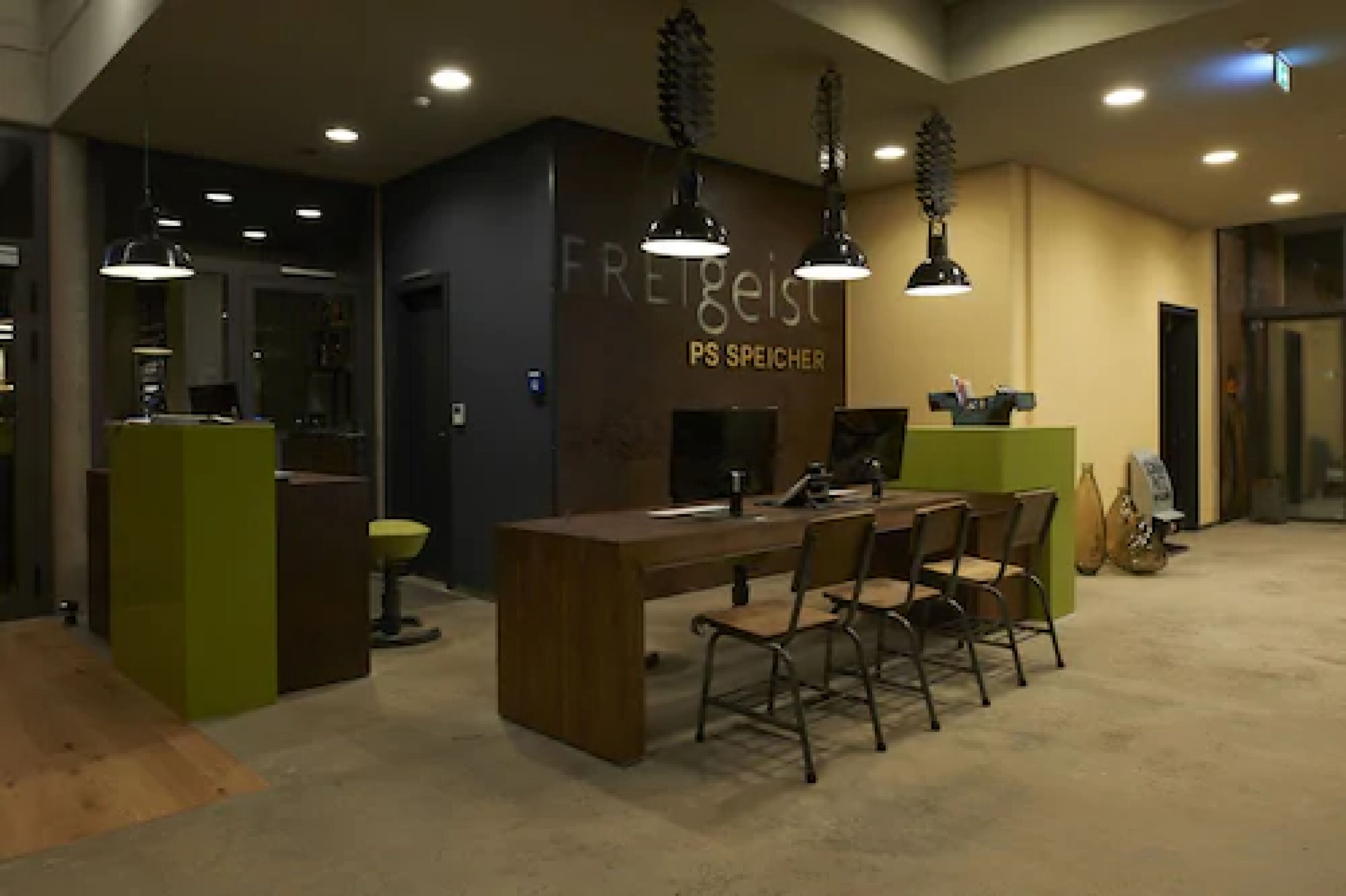A modern hotel lobby with a reception desk, chairs, and pendant lighting.