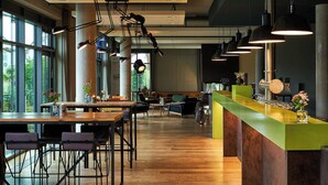 A modern interior with a long wooden bar, seating area, and large windows. - FREIgeist Einbeck - A Member of Design Hotels™ (Einbeck)