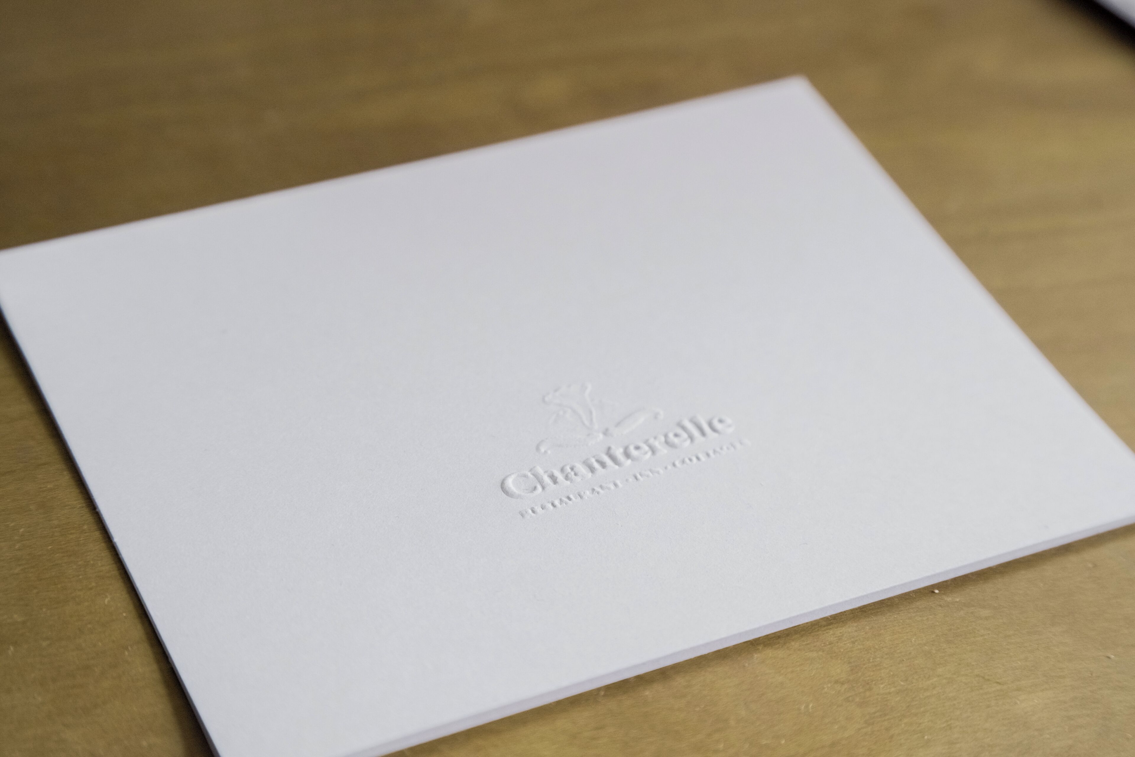 Un folleto blanco con texto en relieve y logotipo.