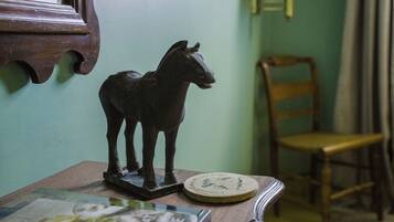 A wooden horse figurine on a table, a chair, and a framed mirror on the wall.