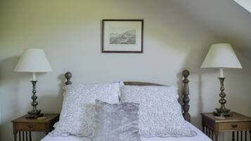 A neatly made bed with patterned pillows, two bedside tables with lamps, and a framed picture on the wall.