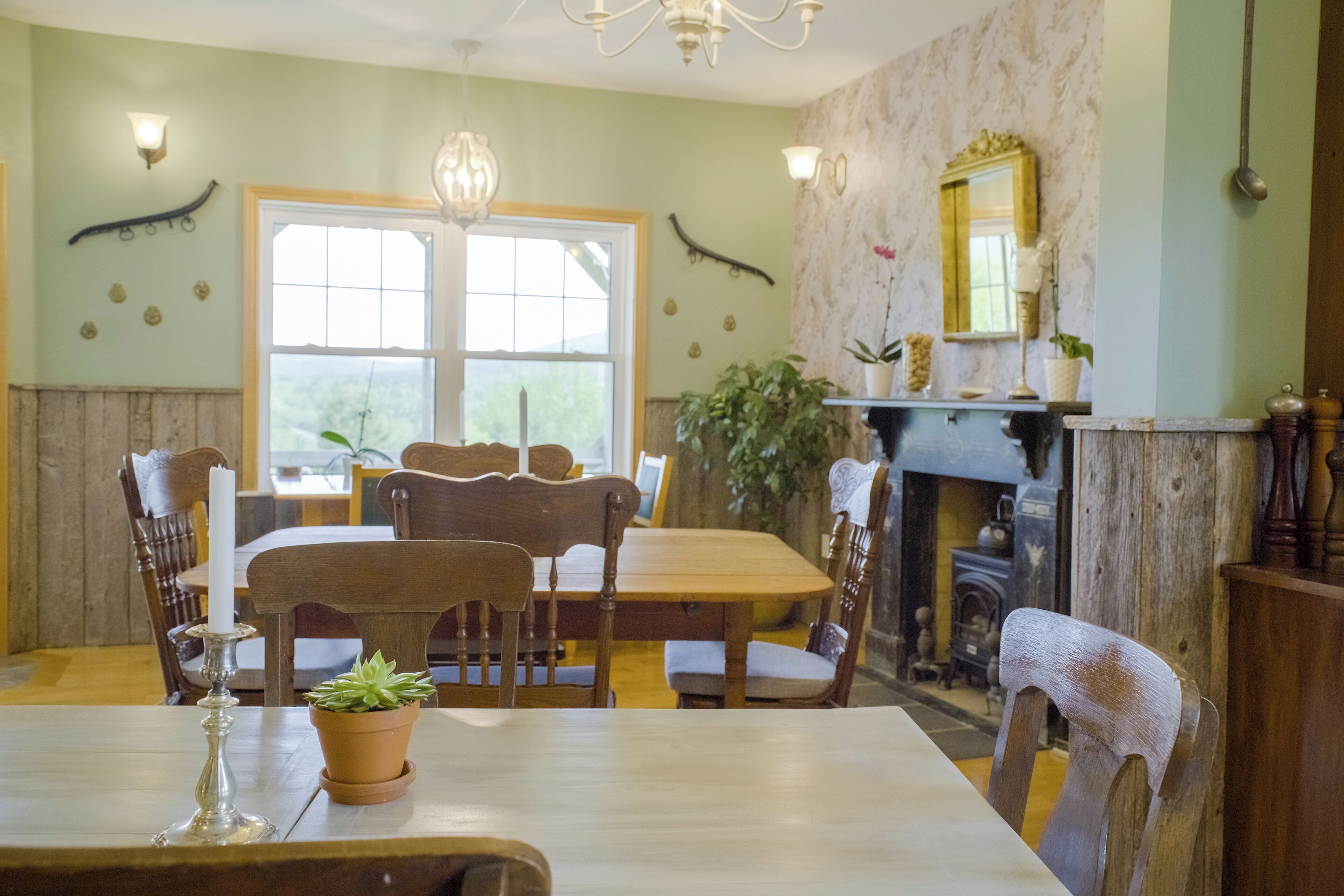 A dining room with a wooden table and chairs, a chandelier, and a fireplace.