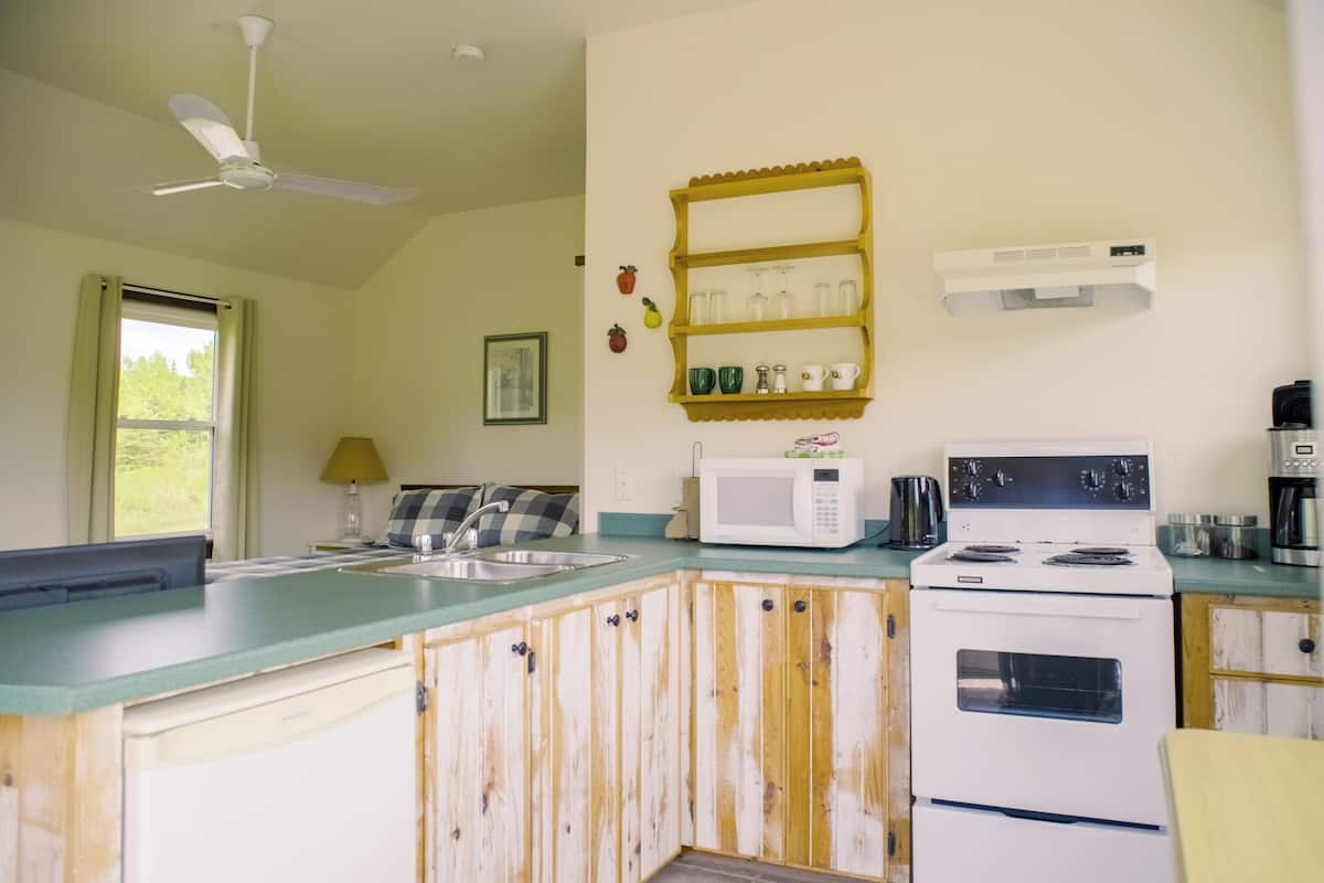 A kitchen with a white stove, a microwave, a sink, and a ceiling fan.