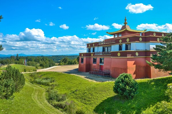 A traditional building with a red and gold exterior, a balcony, and a view of a green landscape. - Chambres d Hotes du Moulin de Lachaux (Chateauneuf-les-Bains)