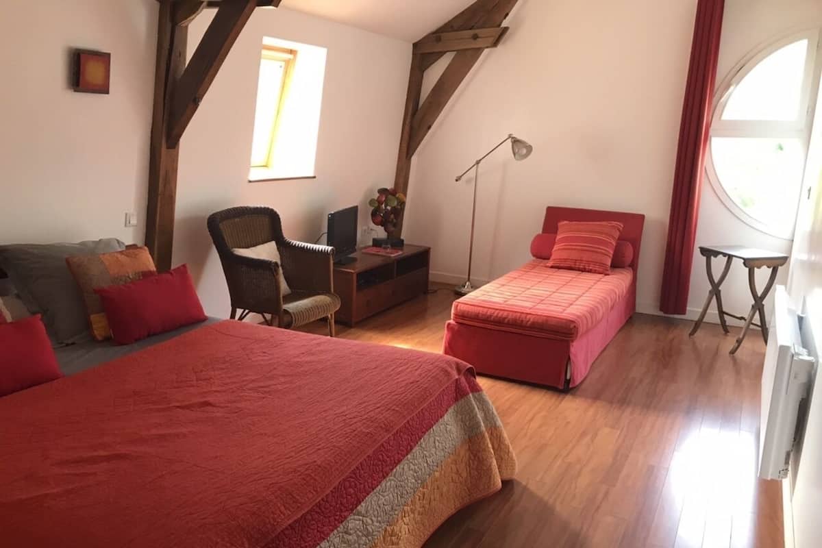A bedroom with two beds, a desk, and a chair.