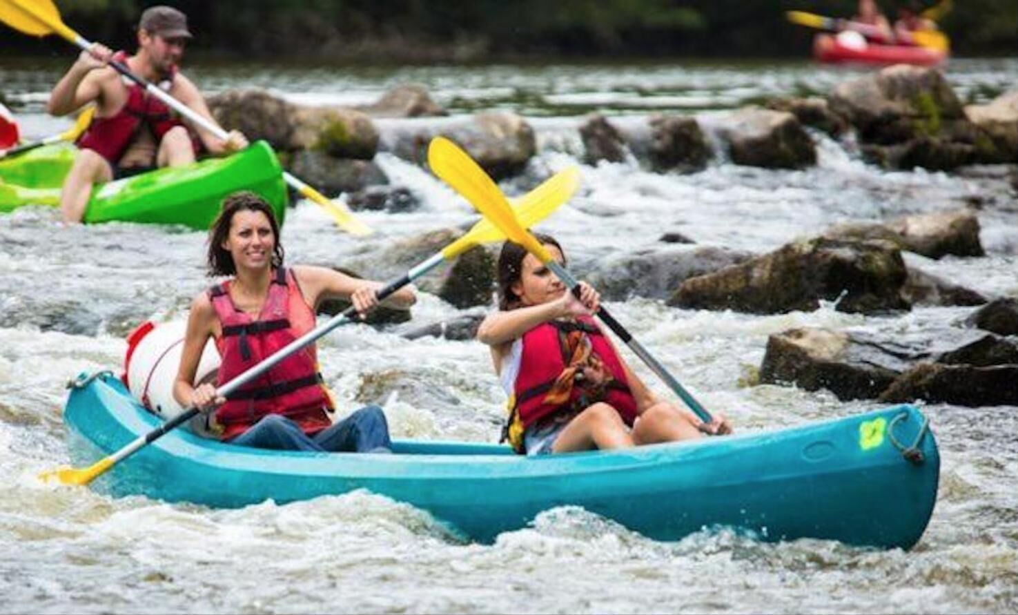People in a blue raft navigating a river with rapids.