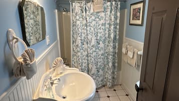 Un baño con lavabo, espejo, cortina de ducha y toallas.