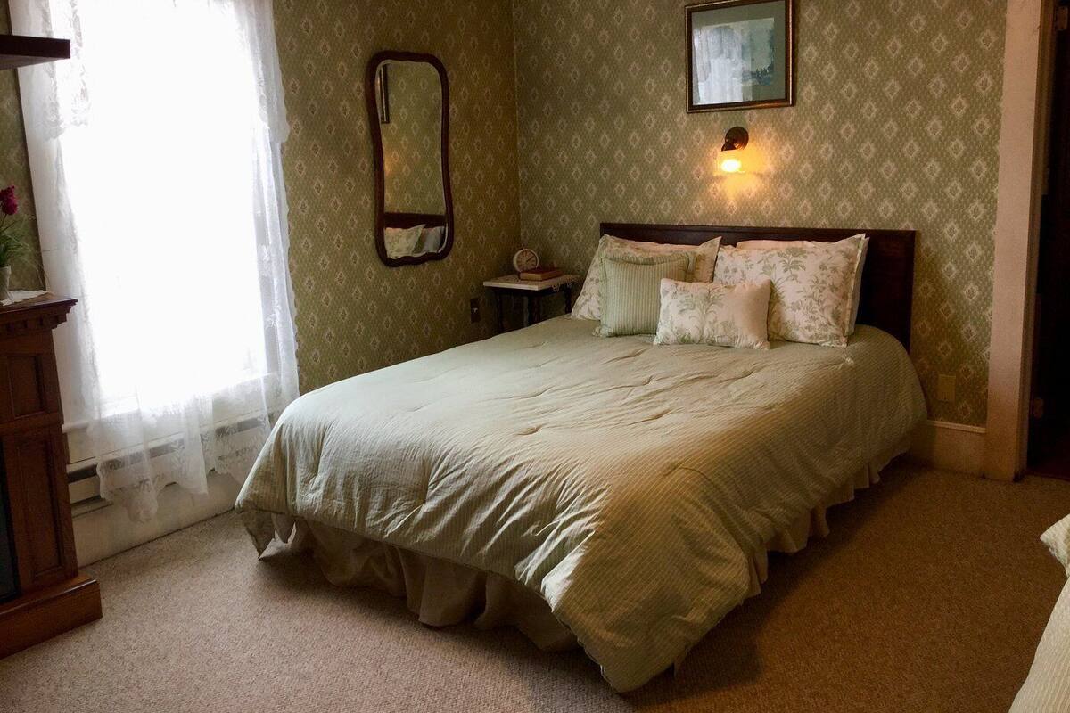 A bedroom with a large bed, a bedside table, a mirror, and a picture on the wall.