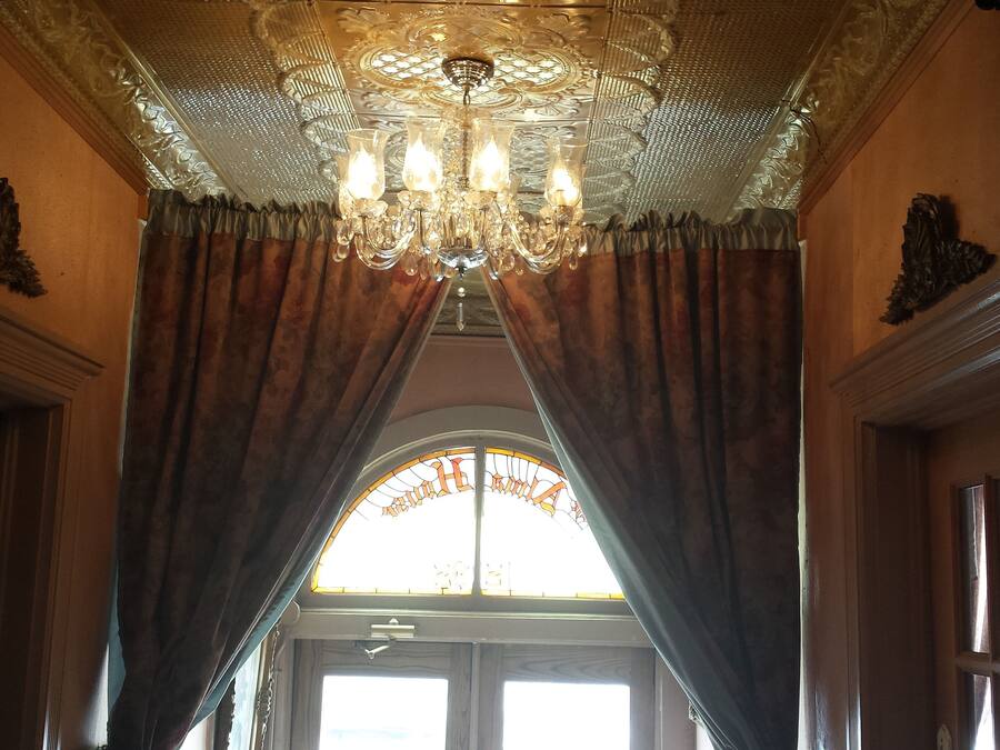 An ornate room with a chandelier, draped curtains, and a stained glass window.