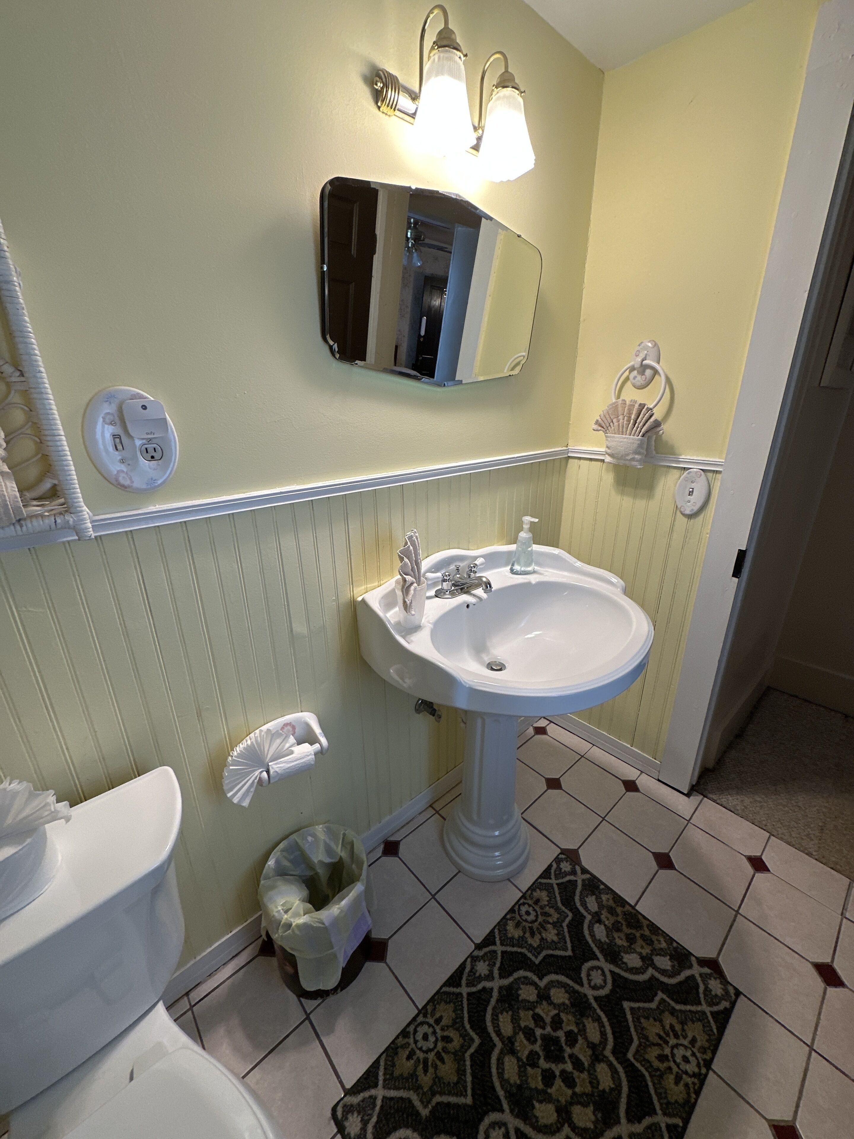 A bathroom with a white sink, a mirror above it, and a light fixture.