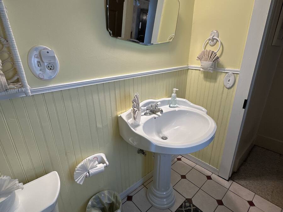 A bathroom with a white sink, a mirror above it, and a light fixture.