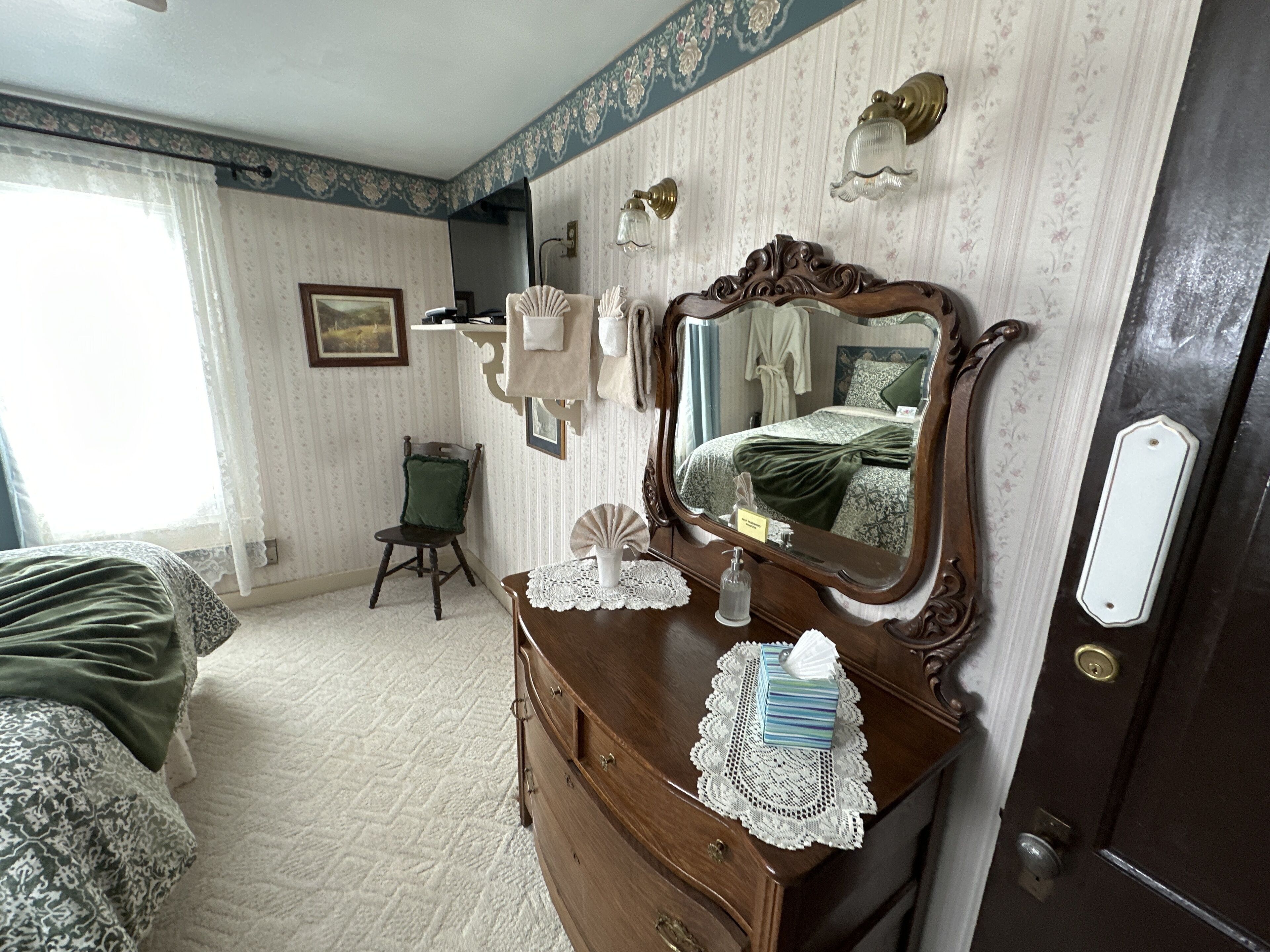 Un dormitorio con un espejo grande, un aparador, una silla y una cama.
