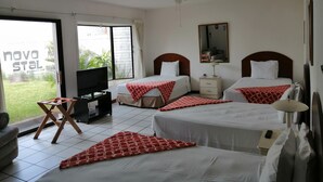 A hotel room with two beds, a TV, a desk, and a balcony with a view. - Novohostal B&B (Guatemala City)