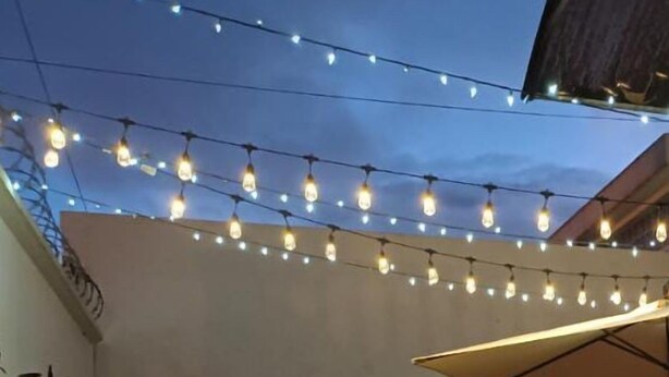 An outdoor patio with string lights, a table, chairs, and potted plants. - Novohostal B&B (Guatemala City)