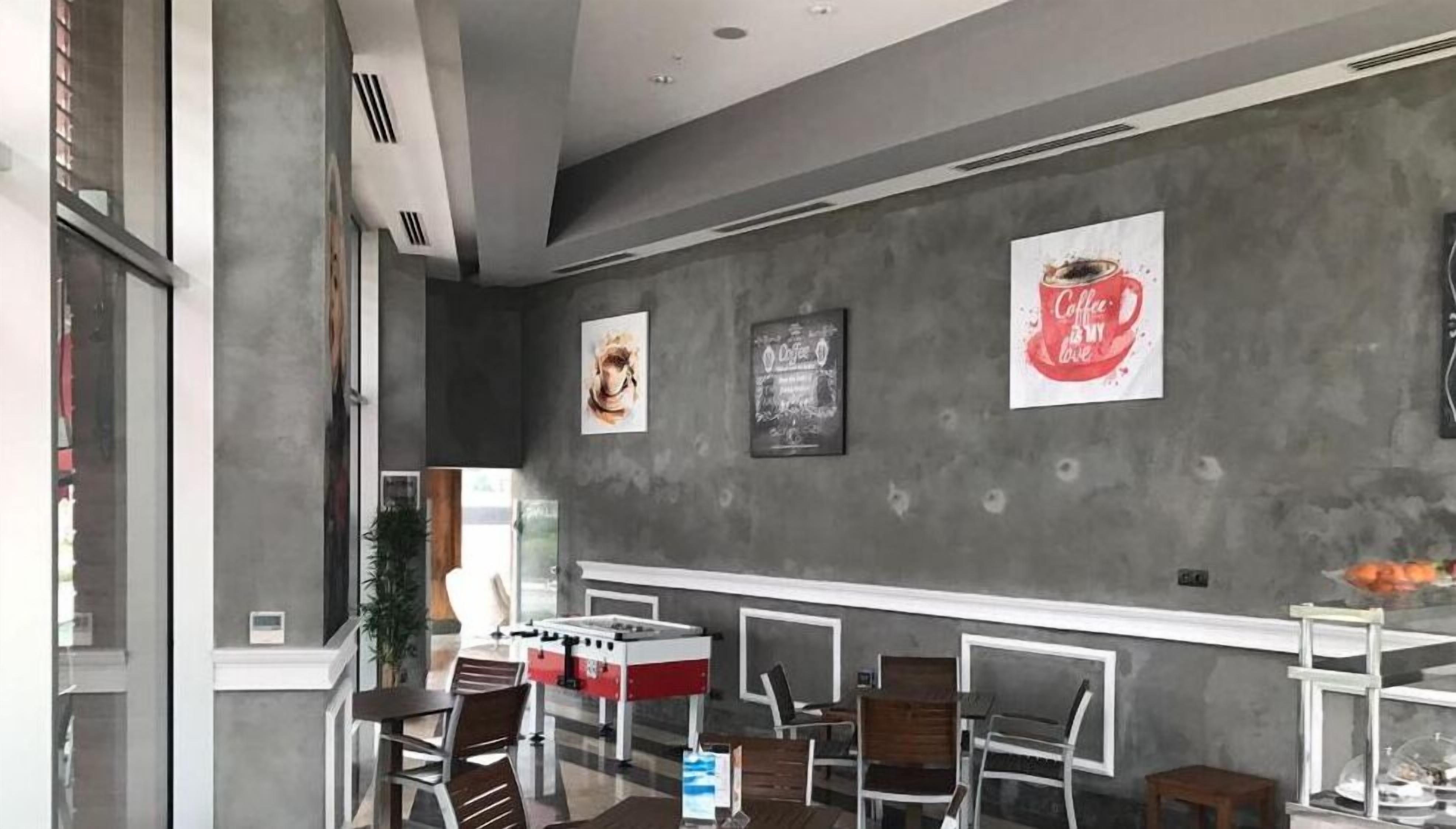Un moderno interior de cafetería con una barra, asientos y obras de arte en las paredes.