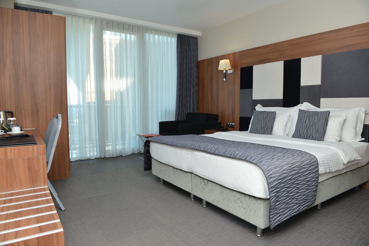 A modern hotel room with a large bed, a desk, and a chair.