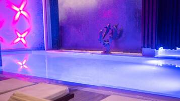 A modern spa area with a large bathtub, a decorative wall with a star pattern, and a tiled floor.