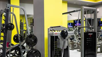 Un gimnasio con equipamiento de levantamiento de pesas variado, que incluye una estructura para sentadillas y una prensa de banca.