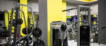 Un gimnasio con equipamiento de levantamiento de pesas variado, que incluye una estructura para sentadillas y una prensa de banca.