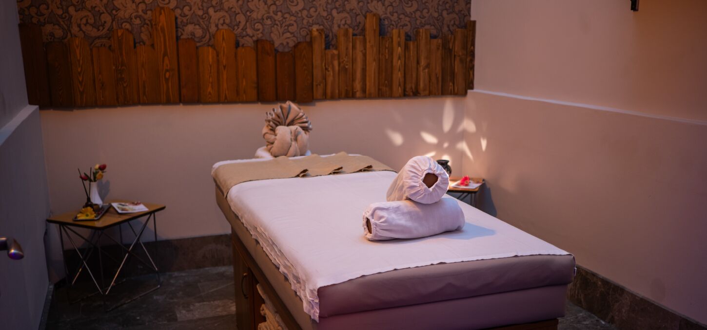 A hotel room with a bed, a small table with a vase of flowers, and a wooden headboard.