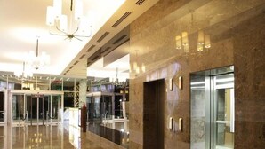 A modern lobby with a marble floor, glass elevator, and a chandelier. - Lova Hotel SPA (Yalova)