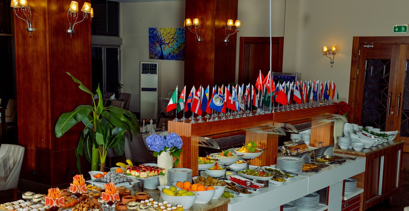 A buffet with various dishes, flags, and a large plant.