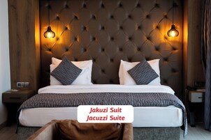 Una suite con jacuzzi, cabecera capitonada, dos lámparas de noche y cama con ropa de cama estampada.